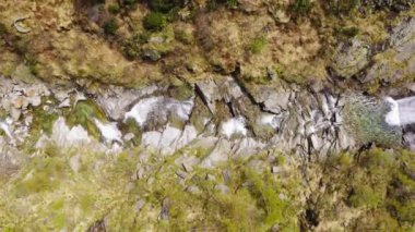 Dağdaki kayalıklardan akan şelale manzarası. Her iki tarafta yeşil orman