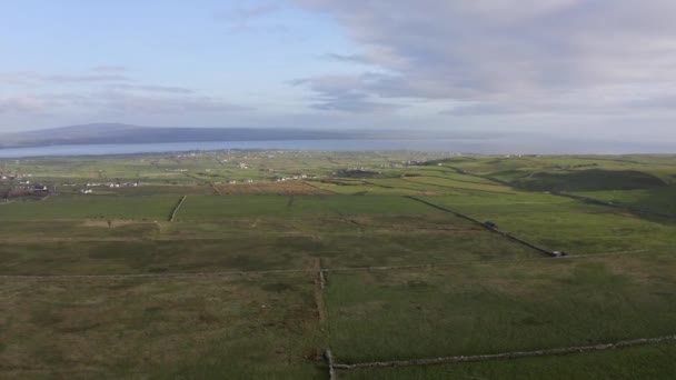 Flygfoto över irish gröna landsbygdsområden under en sommar solnedgång i Irland. Hav och kulle i bakgrunden, moln på himlen. Känsla av frihet, renhet, frihet, orörd, vild natur — Stockvideo