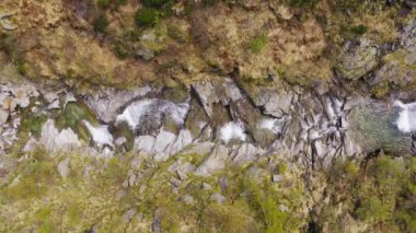 Dağdaki kayalıklardan akan şelale manzarası. İki tarafta da yeşil orman var. Yüksek kalite 4k görüntü