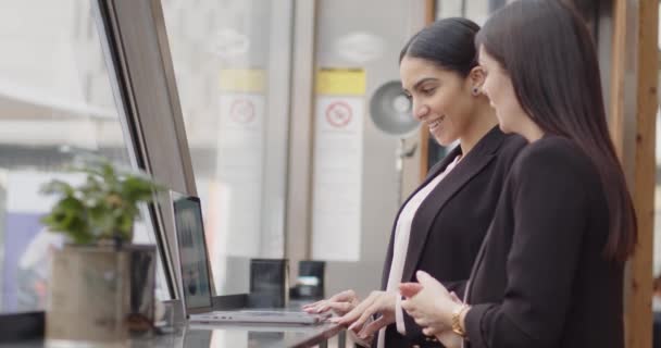 两个女商人站在她们之前就餐的餐馆窗前 两个女人在一家工业风格的餐馆窗前用笔记本电脑谈论金融数据 — 图库视频影像