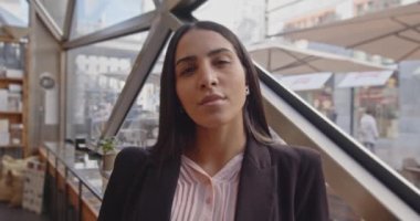 Etnik iş kadını kameraya bakıyor. Bir meslektaşla konuşan bir kadının portresi. Çok ırklı bir kadının çok yönlü konuşması, barda bir arkadaşıyla gülümsemesi. Yüksek kalite 4k görüntü