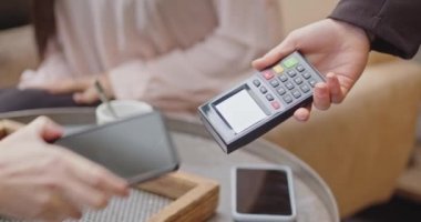 Elektronik ödeme makinesinden ya da kart okuyucudan ödemeyi telefonla yapın. Nakitsiz cüzdanda e-para. Kadın müşterinin eli, kadın satıcının postal terminalinde ya da kahve dükkanında ya da restoranda çalışan birinin üzerinde.