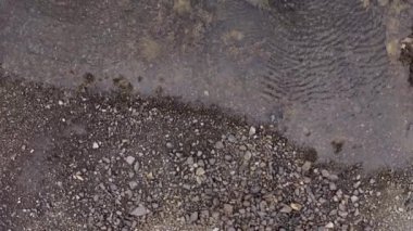Dalgaların alçak deniz manzarası. Kayalardan ve yosunlardan oluşan alçak sularda mavi bir tekne. Düşük gelgitte İrlanda kıyı şeridine insansız hava aracı bakış açısı. Yüksek kalite 4k görüntü