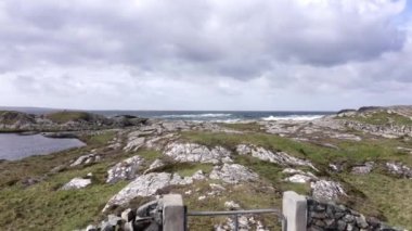 İrlanda kıyılarının havadan görünüşü, yeşil alanlar, kayalar, bulutlu bir günde arka planda dalgalı deniz. Rocky duvarlı yapılar, antika, karakteristik. Yüksek kalite 4k görüntü