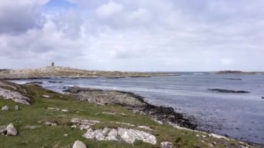 Dalgaların alçak deniz manzarası. Güzel insansız hava aracı İrlanda kıyılarında alçak gelgitte uçuyor arka plandaki deniz fenerinde yeşil tarlalar bulutlu bir günde sakin bir deniz. Yüksek kalite 4k görüntü