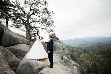 Harika bir gelin damada poz veriyor ve harika manzaralı dağlarda eğleniyor. Mesajlaşacak yer, düğün çifti.