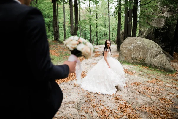 Stylový pár šťastných novomanželů. Nevěsta běží od ženicha v parku v jejich svatební den s kyticí — Stock fotografie