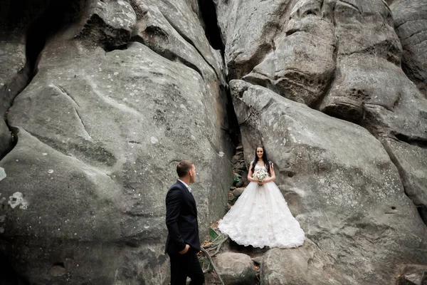 Великолепная невеста, позирующая груму и веселящаяся у гор с изумительным видом, место для текста, свадебная пара — стоковое фото