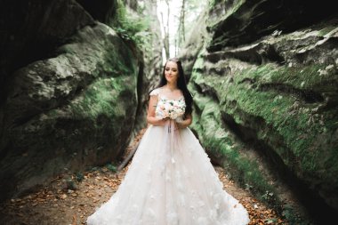 Çekici gelinin portresi, uzun saçlı, büyük buketli poz veren.