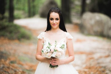 Lüks bir gelin, bir kız buketle poz veriyor ve gülümsüyor.