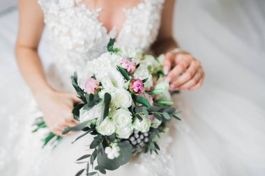 Gelin çiçekli büyük ve güzel bir düğün buketi tutuyor.