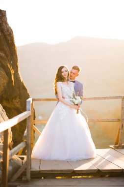 Doğadaki düğün çifti birbirine sarılıyor. Beyaz elbiseli güzel bir kız. Takım elbiseli adam