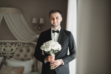 Güzel adam, damat elinde çiçeklerle büyük ve güzel bir düğün buketi tutuyor