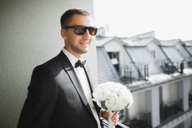 Güzel adam, damat elinde çiçeklerle büyük ve güzel bir düğün buketi tutuyor