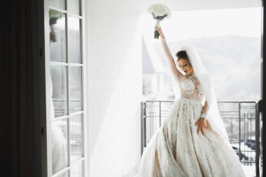 Lüks bir gelin, bir kız buketle poz veriyor ve gülümsüyor.