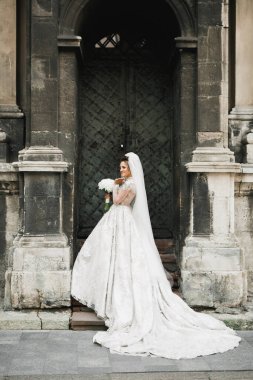 Gelin çiçekli büyük ve güzel bir düğün buketi tutuyor.