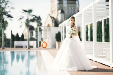 Parkta poz veren zarif beyaz elbiseli güzel gelin.