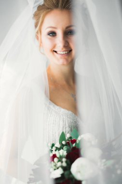 Cüppeli muhteşem gelin bir odada düğün töreni için poz veriyor ve hazırlanıyor.