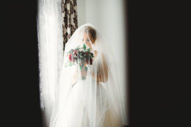 Lüks bir gelin, bir kız buketle poz veriyor ve gülümsüyor.