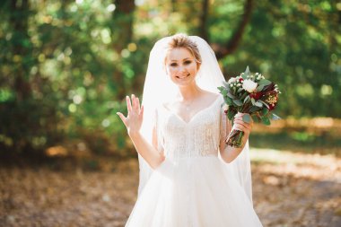 Lüks bir gelin, bir kız buketle poz veriyor ve gülümsüyor.