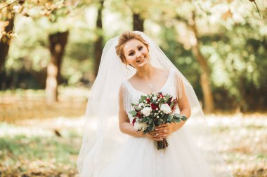 Lüks bir gelin, bir kız buketle poz veriyor ve gülümsüyor.