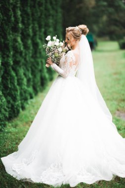 Lüks bir gelin, bir kız buketle poz veriyor ve gülümsüyor.