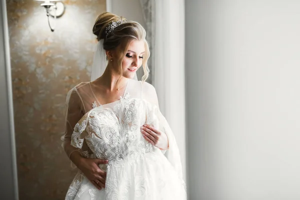 Mempelai wanita cantik mengenakan gaun pengantin dengan bulu dengan riasan mewah dan gaya rambut, studio pemotretan dalam ruangan — Stok Foto