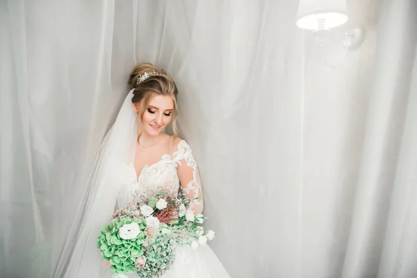 Hermosa novia con vestido de novia de moda con plumas con maquillaje de lujo deleite y peinado, estudio sesión de fotos interior — Foto de Stock