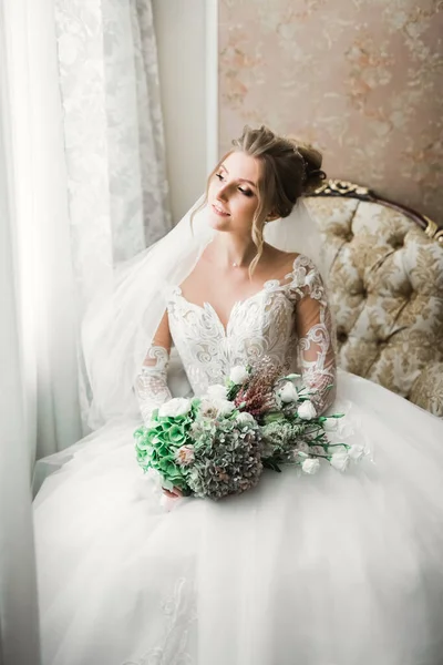 Mempelai wanita cantik mengenakan gaun pengantin dengan bulu dengan riasan mewah dan gaya rambut, studio pemotretan dalam ruangan — Stok Foto