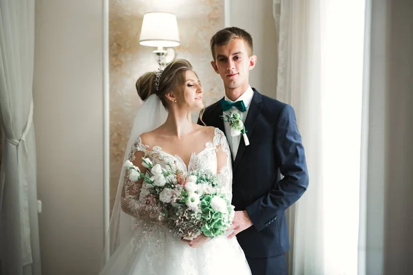 Bella giovane coppia di nozze in posa con mazzo di fiori in mano — Foto Stock