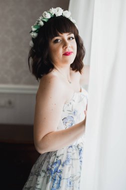 Cüppeli muhteşem gelin bir odada düğün töreni için poz veriyor ve hazırlanıyor.