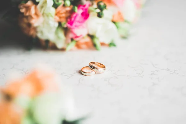 Hermosa imagen tonificada con anillos de boda sobre el fondo de un ramo de flores — Foto de Stock