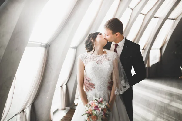Прекрасна щаслива весільна пара, наречена з довгим білим платтям позує в красивому місті — стокове фото