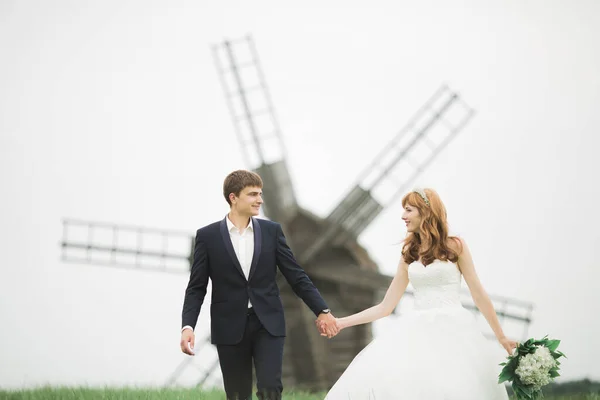 Elegante pareja de recién casados felices caminando en el parque el día de su boda con ramo —  Fotos de Stock