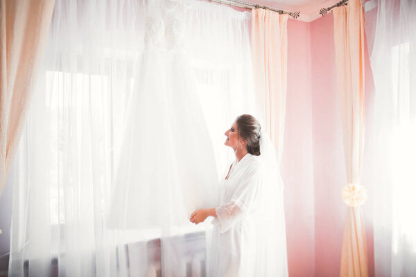 Luxury bride in white dress posing while preparing for the wedding ceremony