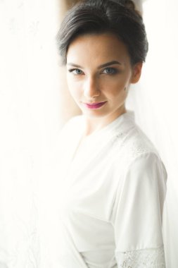 Cüppeli muhteşem gelin bir odada düğün töreni için poz veriyor ve hazırlanıyor.