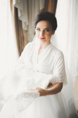 Cüppeli muhteşem gelin bir odada düğün töreni için poz veriyor ve hazırlanıyor.