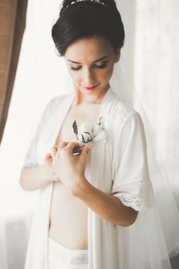 Cüppeli muhteşem gelin bir odada düğün töreni için poz veriyor ve hazırlanıyor.