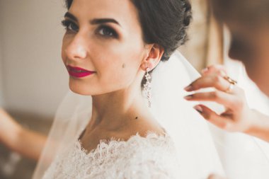 Cüppeli muhteşem gelin bir odada düğün töreni için poz veriyor ve hazırlanıyor.