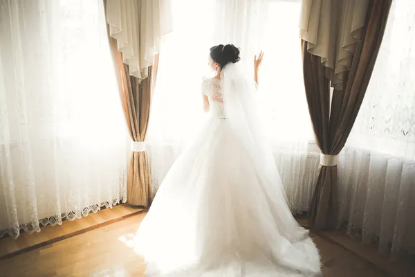 Preciosa novia en bata posando y preparándose para la ceremonia de boda cara en una habitación — Foto de Stock