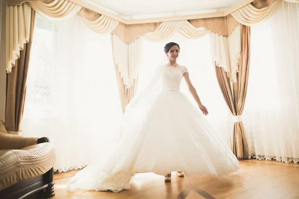 Prachtige bruid in badjas poseren en voor te bereiden op de bruiloft ceremonie gezicht in een kamer — Stockfoto
