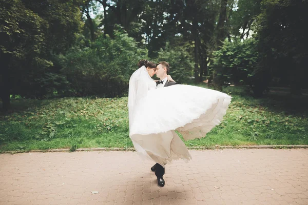 Romântico, conto de fadas, feliz casal recém-casado abraçando e beijando em um parque, árvores no fundo — Fotografia de Stock