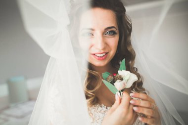 Cüppeli muhteşem gelin bir odada düğün töreni için poz veriyor ve hazırlanıyor.