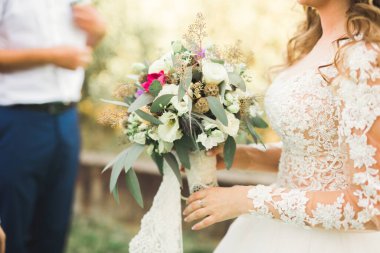 Çiçek buketi taşıyan mükemmel bir düğün çifti.