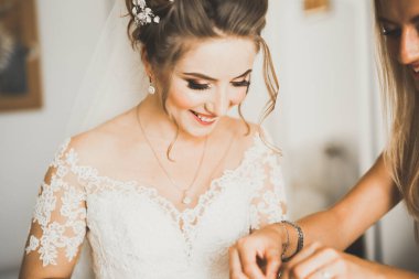 Cüppeli muhteşem gelin bir odada düğün töreni için poz veriyor ve hazırlanıyor.