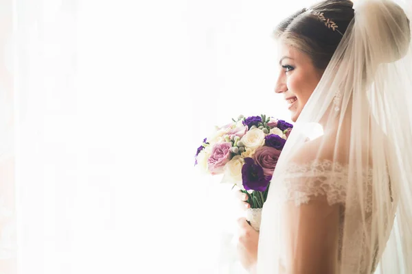 Hermosa novia con vestido de novia de moda con plumas con maquillaje de lujo deleite y peinado, estudio sesión de fotos interior — Foto de Stock