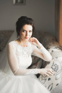 Cüppeli muhteşem gelin bir odada düğün töreni için poz veriyor ve hazırlanıyor.