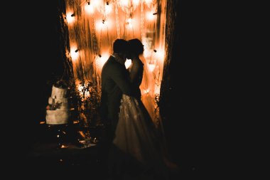 Akşam nikâhı. Gelin ve damat ışıkların ve fenerlerin arkasında el ele tutuşuyorlar.