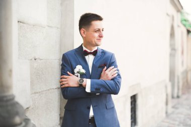 Yaka çiçeğiyle poz veren mutlu yakışıklı damat..