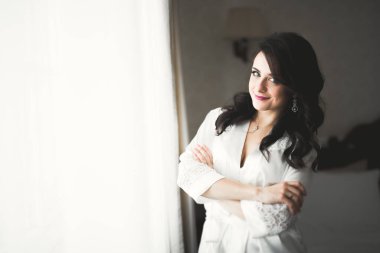 Cüppeli muhteşem gelin bir odada düğün töreni için poz veriyor ve hazırlanıyor..